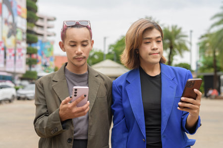 Asian gender diverse business coworker professionals using technology on city street