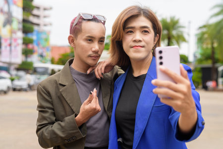 Asian gender diverse business coworker professionals using technology on city streetの写真素材