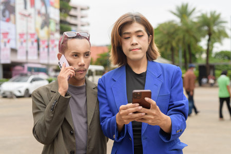 Asian gender diverse business coworker professionals using technology on city street