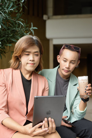 Asian transgender woman and non-binary coworkers working remotely in cafe