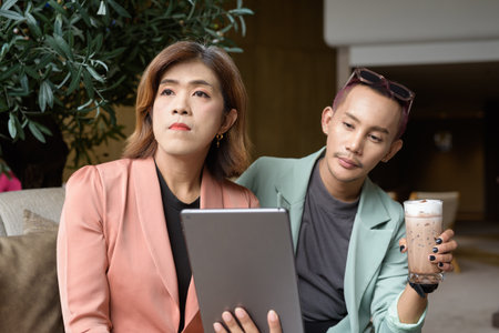 Asian transgender woman and non-binary coworkers working remotely in cafeの写真素材