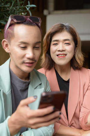 Asian transgender woman and non-binary coworkers working remotely in cafeの写真素材