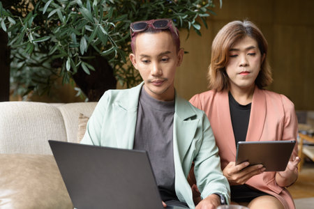Asian transgender woman and non-binary coworkers working remotely in cafeの写真素材