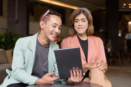 Asian transgender woman and non-binary coworkers working remotely in cafeの写真素材