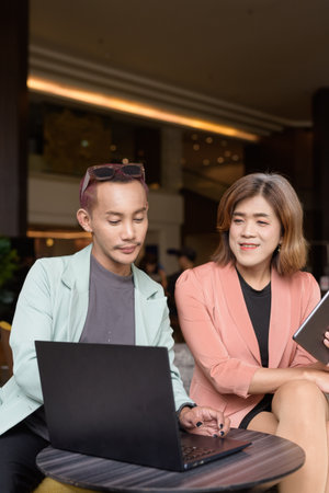 Asian transgender woman and non-binary coworkers working remotely in cafeの写真素材