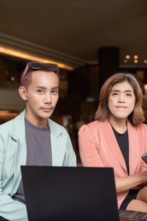 Asian transgender woman and non-binary coworkers working remotely in cafeの写真素材