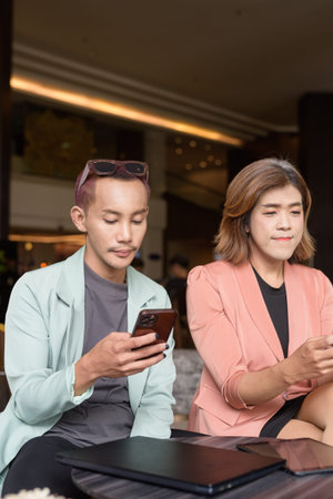 Asian transgender woman and non-binary coworkers working remotely in cafe