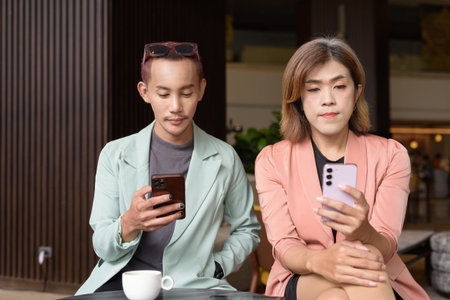 Asian transgender woman and non-binary coworkers working remotely in cafe