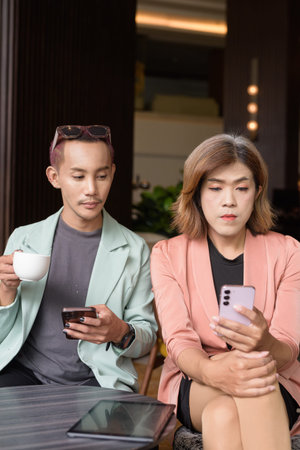 Asian transgender woman and non-binary coworkers working remotely in cafe