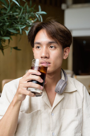 Non binary cute Asian student man sitting in modern coffee shop