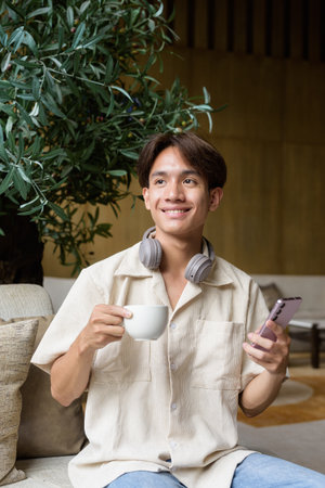 Non binary cute Asian student man sitting in modern coffee shopの写真素材