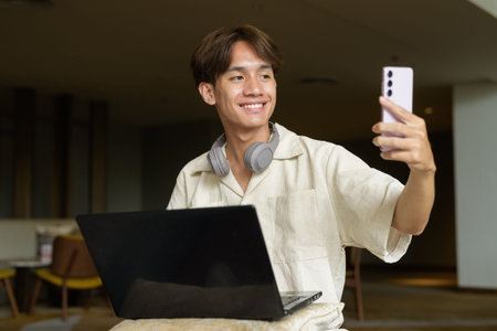 Non binary cute Asian student man sitting in modern coffee shop