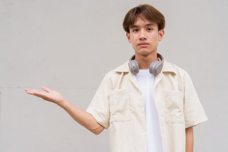 Non binary cute Asian young gay man portrait against plain background