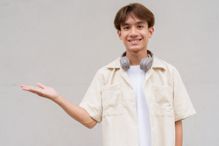 Non binary cute Asian young gay man portrait against plain background