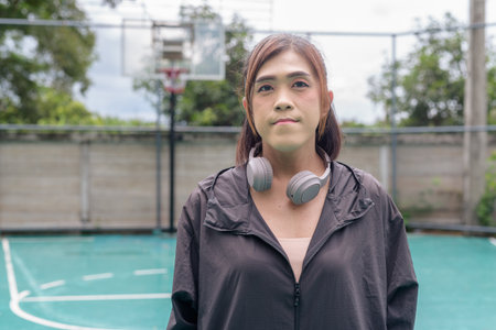 Portrait of a fit transgender woman standing on outdoor basketball court, promoting strength and urban fitness lifestyleの写真素材
