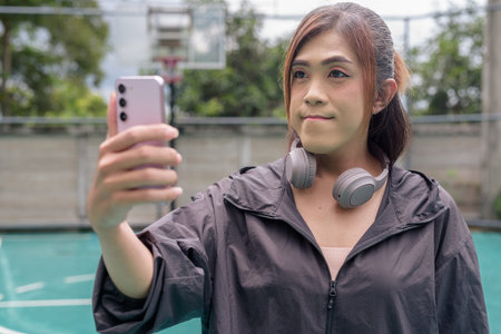 Portrait of a fit transgender woman standing on outdoor basketball court, promoting strength and urban fitness lifestyleの写真素材