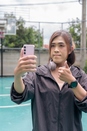 Portrait of a fit transgender woman standing on outdoor basketball court, promoting strength and urban fitness lifestyleの写真素材