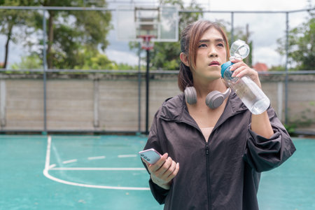 Portrait of a fit transgender woman standing on outdoor basketball court, promoting strength and...