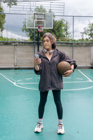 Portrait of a fit transgender woman standing on outdoor basketball court, promoting strength and urban fitness lifestyleの写真素材