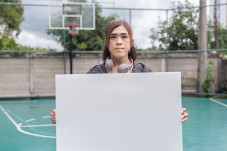 Portrait of a fit transgender woman standing on outdoor basketball court, promoting strength and urban fitness lifestyleの写真素材