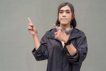 Portrait of a transgender Asian woman in front of a plain outdoors wall wearing sports clothingの写真素材