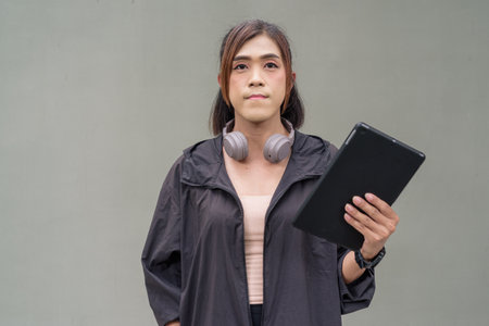Portrait of a transgender Asian woman in front of a plain outdoors wall wearing sports clothingの写真素材