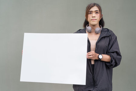 Portrait of a transgender Asian woman in front of a plain outdoors wall wearing sports clothing