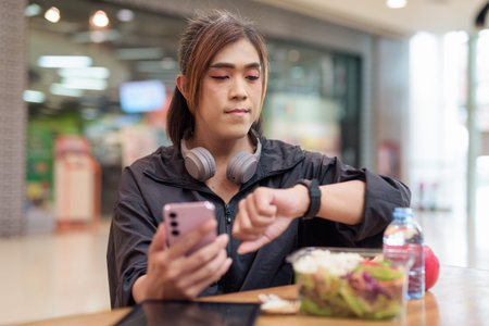 Mature transgender woman eating healthy salad with apple and water in casual mall restaurant...