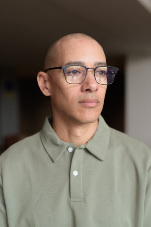 Latin man in his 40s posing in hotel cafe or bar with modern interior. Headshot focused on elegant...