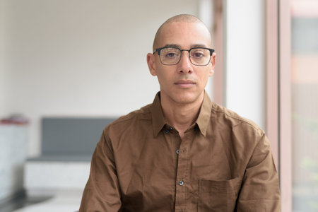 Bald Hispanic man in his 40s wearing casual shirt and eyeglasses. Confident and happy expression....