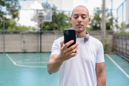 Bald Hispanic man in sportswear posing on basketball court. Urban sports lifestyle, combining confidence, athleticism and healthy outdoor fitness vibe.の写真素材