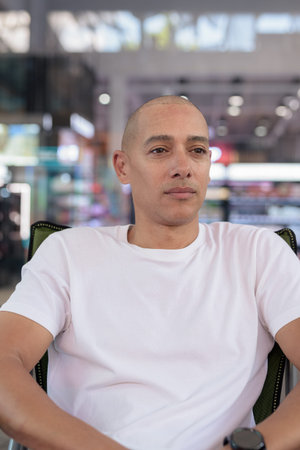Hispanic man in his 40s posing confidently in an outdoor coffee shop restaurant. Warm, healthy, relaxed portrait showing modern urban lifestyle and personality in natural light.の写真素材