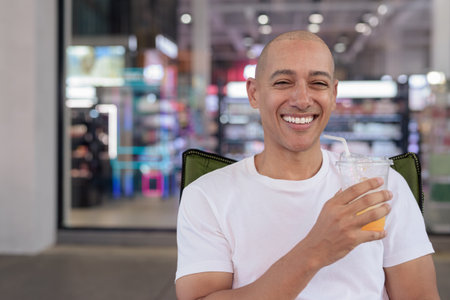 Hispanic man in his 40s posing confidently in an outdoor coffee shop restaurant. Warm, healthy, relaxed portrait showing modern urban lifestyle and personality in natural light.の写真素材