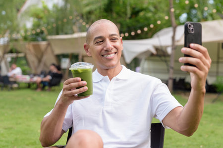 Stylish bald man in a white polo shirt relaxing at a campsite. Outdoor travel and camping lifestyle...