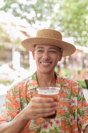 A Hispanic male enjoying an iced coffee while sitting at an outdoor cafe on a sunny day, wearing a...