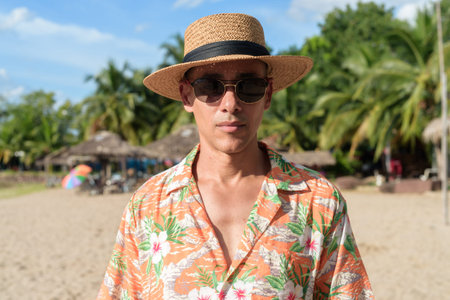 Hispanic man wearing a Panama hat and Hawaiian shirt, dressed in casual summer vacation style. He...
