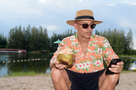 Hispanic man wearing a Panama hat and Hawaiian shirt, dressed in casual summer vacation style. He poses at beach, showing a relaxed holiday atmosphere with resort fashion for beach or island travel.の写真素材