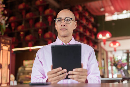 Bald Hispanic mature male in 40s wearing pink casual business shirt and eyeglasses in Chinese style...