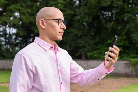 Bald Hispanic mature male in 40s wearing pink shirt and eyeglasses outdoors with camping park...