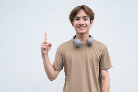 Handsome young Asian Thai man with headphones enjoying modern lifestyle portrait against white backgroundの写真素材