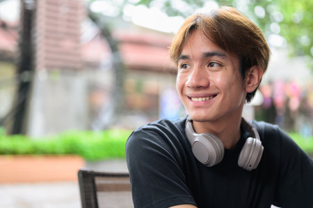 Portrait of a young Thai Asian man smiling in casual style posing for modern lifestyle photography. Confident, relaxed, and authentic look suitable for various concepts and usesの写真素材