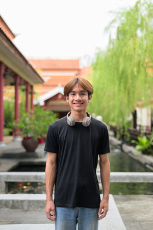 Young Thai Asian man in traditional Asian Zen garden during summer. Confident, relaxed, and...