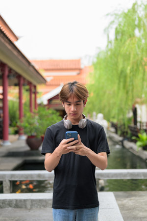 Young Thai Asian man in traditional Asian Zen garden during summer. Confident, relaxed, and authentic look suitable for various concepts and usesの写真素材