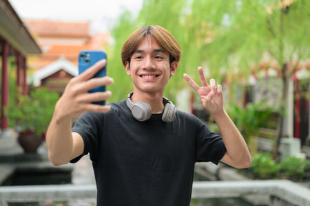 Young Thai Asian man in traditional Asian Zen garden during summer. Confident, relaxed, and authentic look suitable for various concepts and usesの写真素材
