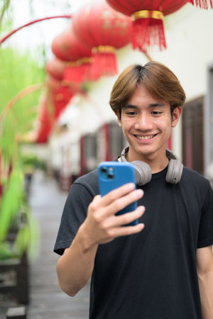 Young Thai Asian man in traditional Asian Zen garden during summer. Confident, relaxed, and authentic look suitable for various concepts and usesの写真素材