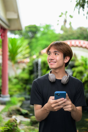 Young Thai Asian man in traditional Asian Zen garden during summer. Confident, relaxed, and authentic look suitable for various concepts and usesの写真素材