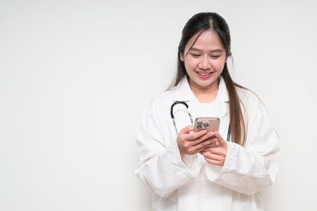 Studio portrait of Southeast Asian Thai healthcare worker woman doctor in lab coat against white background posing confidentlyの写真素材