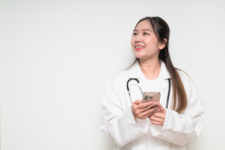 Studio portrait of Southeast Asian Thai healthcare worker woman doctor in lab coat against white background posing confidentlyの写真素材