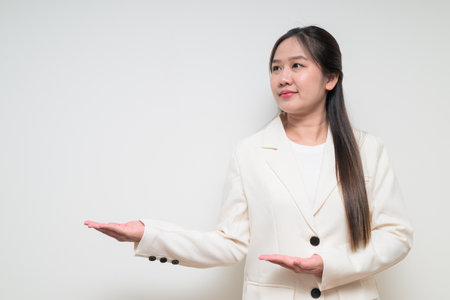 Studio portrait of young Asian woman wearing suit ready for business against white background showing copy spaceの写真素材