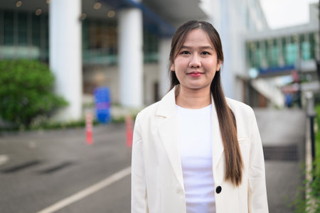Portrait of Southeast Asian businesswoman outdoors in the city street during day wearing business...